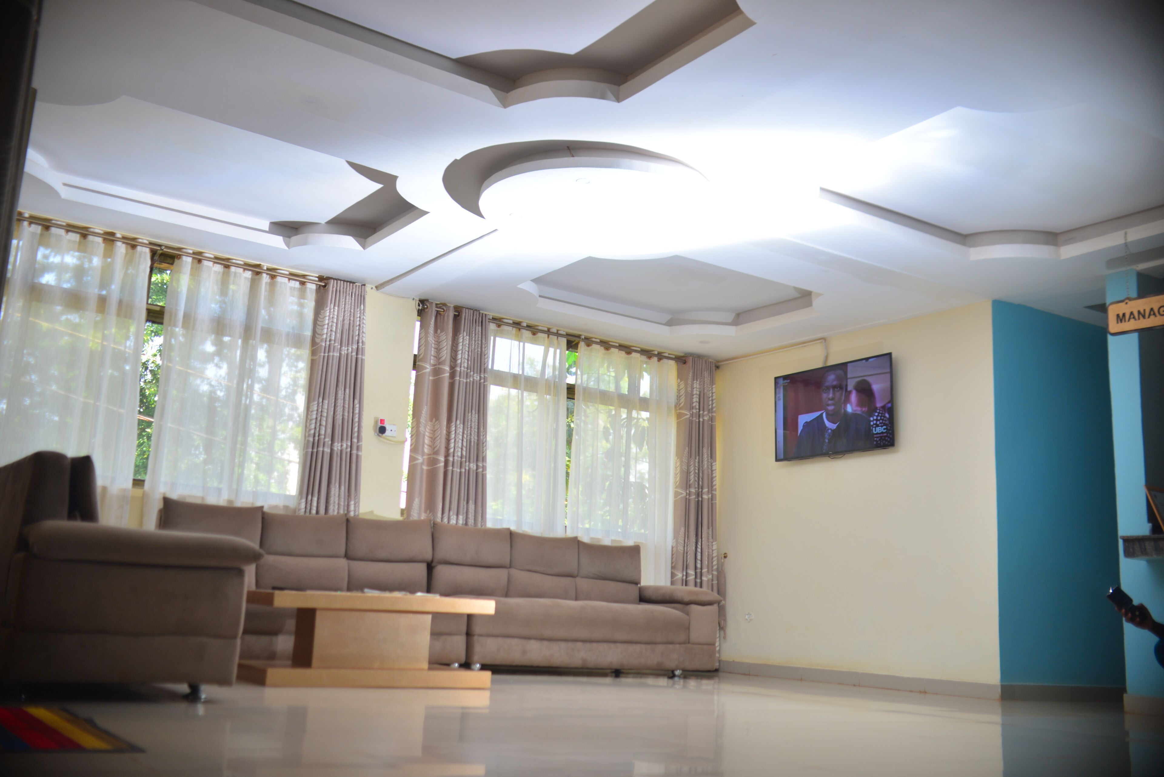 Una sala de estar moderna con sofá, televisor y un techo de diseño único.