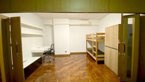 Ein Zimmer mit Fischgrätparkett, Etagenbetten, einem Schreibtisch und einem Stuhl.