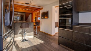 Una cucina moderna con elettrodomestici in acciaio inossidabile, elementi in legno e un angolo bar con sgabelli.