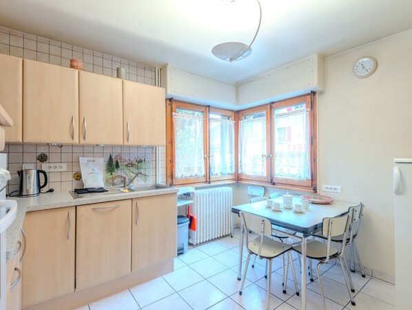 A kitchen with wooden cabinets, a kettle, and a table with chairs.