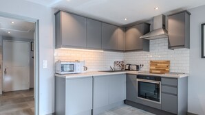 A modern kitchen with grey cabinets, a microwave, toaster, and oven. - Renovated 3-room apartment in Morzine, near center, includes WiFi (Morzine)
