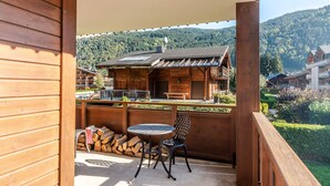 A wooden balcony with a table and chair, overlooking a mountain landscape. - Comfortable 4-room in Morzine, terrace, garage, near center (Morzine)