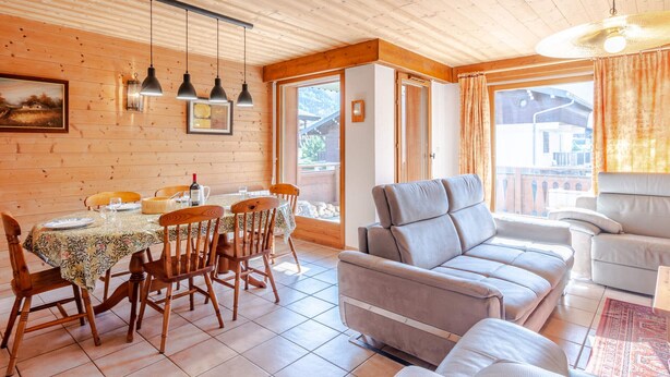 A cozy wooden interior with a dining area, a sofa, and a view of the outside. - Comfortable 4-room in Morzine, terrace, garage, near center (Morzine)