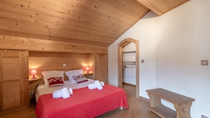 Ett sovrum med träinredning, en säng, sänglampor och en bänk.