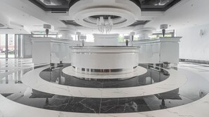A modern lobby with a central circular reception desk, polished marble floors, and contemporary lighting fixtures.