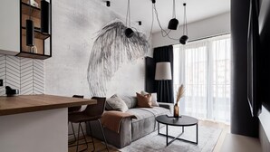 A modern living space with a large abstract mural, a sofa, a coffee table, and a dining area with a wooden counter and chairs.