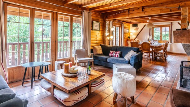A cozy log cabin interior with a dining area, a sofa, and a fireplace.