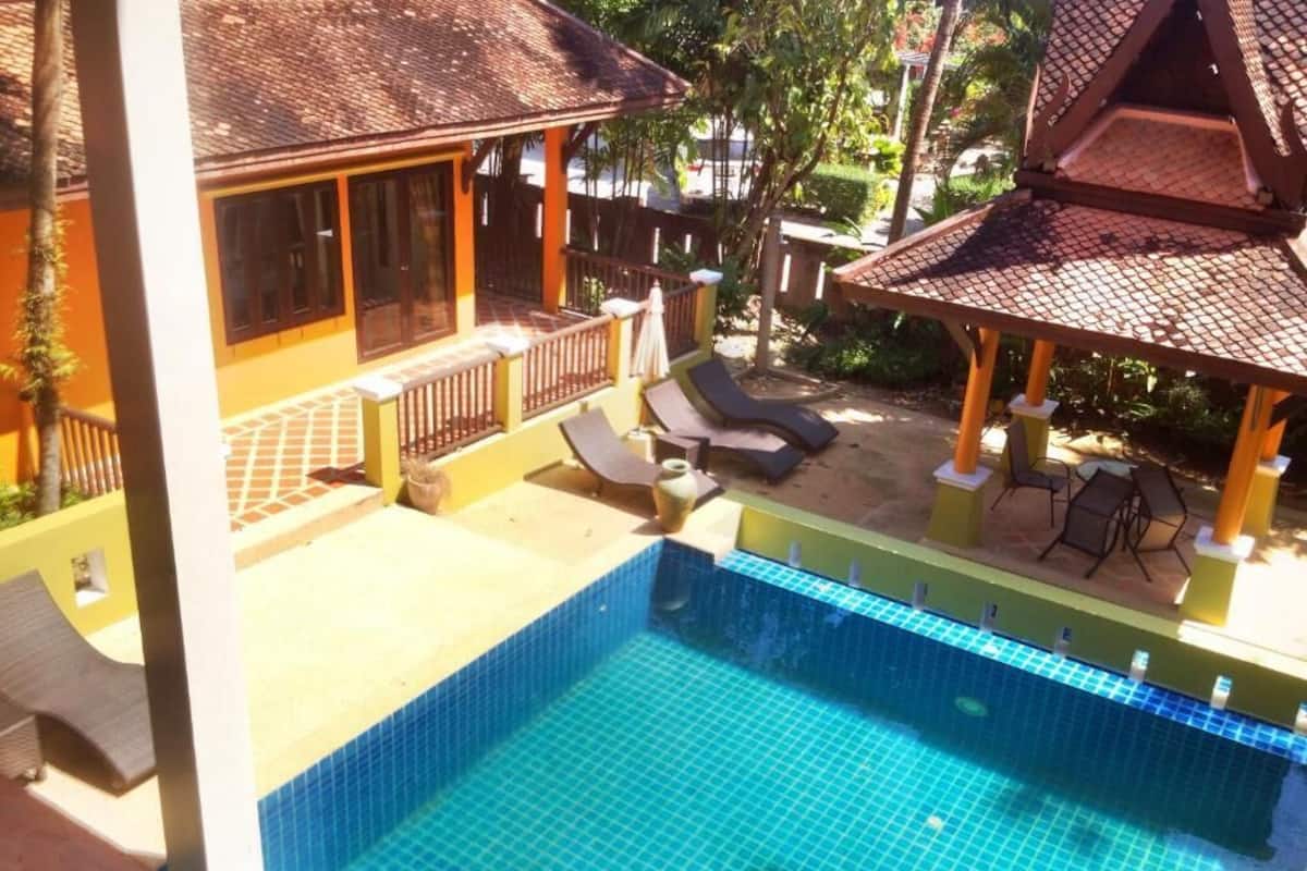 A pool area with lounge chairs and a covered seating area.