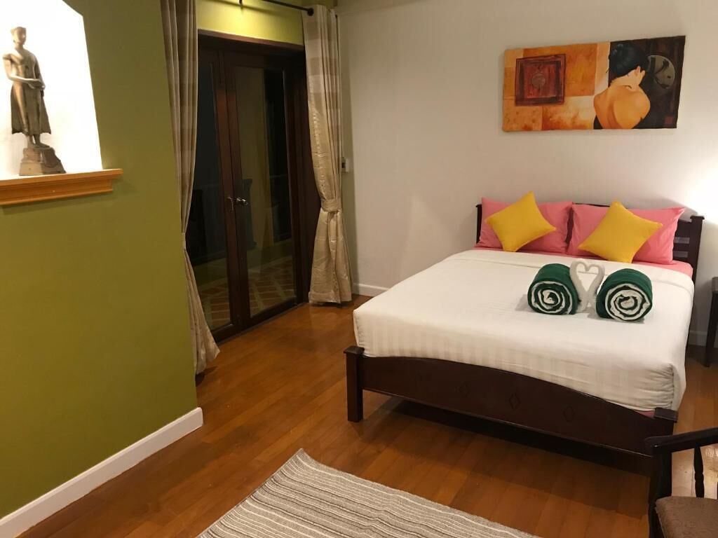 Un dormitorio con una cama, almohadas, un cuadro y una estatua.
