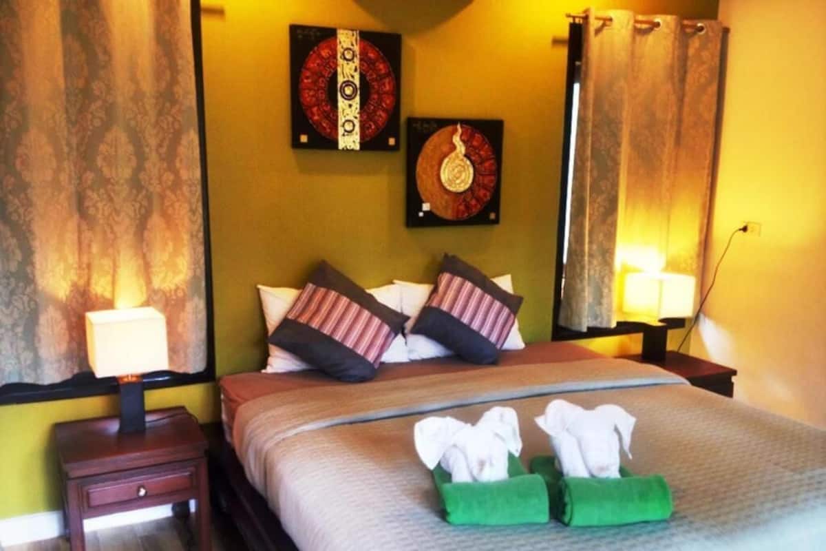 A hotel room with a bed, two nightstands, and two wall-mounted lamps.