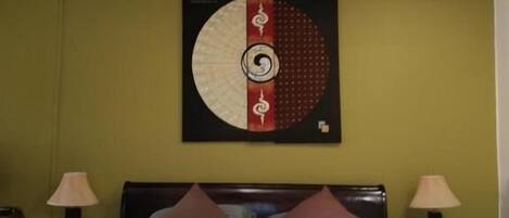 Una habitación de hotel con una cama, una obra de arte en la pared y dos lámparas de noche.