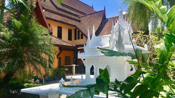 Un bâtiment traditionnel avec un toit en tuiles et une structure blanche ornée au premier plan.