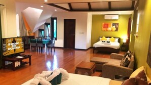 Une chambre d’hôtel comprenant un lit, un canapé, une télévision et un coin repas avec des chaises et une table.