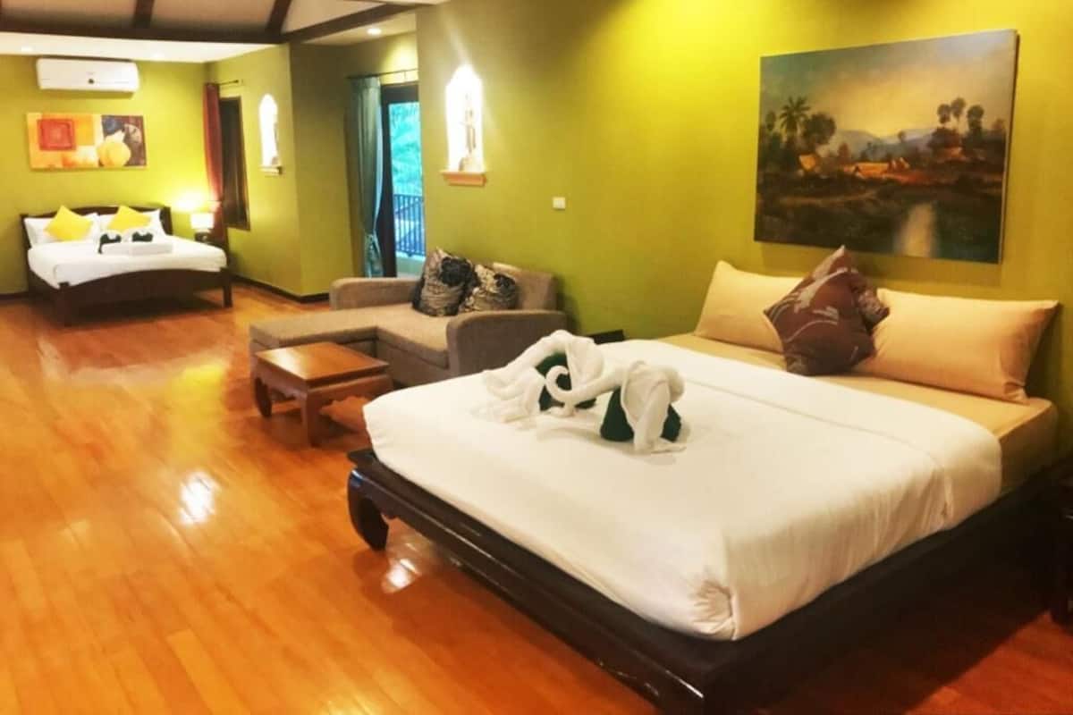 A hotel room with a large bed, a sofa, a small table, and a painting on the wall.