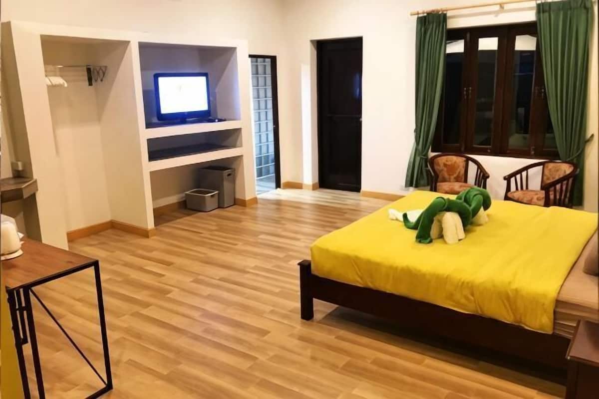 A bedroom with a bed, a desk, a chair, a TV, and a wardrobe.