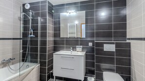 Une salle de bain moderne avec une douche à parois de verre, un lavabo blanc et des toilettes.