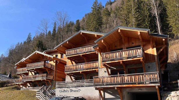 Un bâtiment de style chalet, doté de nombreux balcons et d’une entrée en pierre.