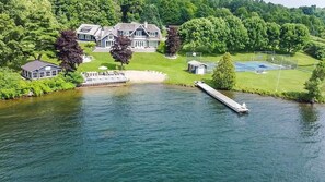 A large house with a dock extending into a lake, surrounded by lush greenery. - Exclusive Waterfront Getaway with Beach & Bunkie (Portland)
