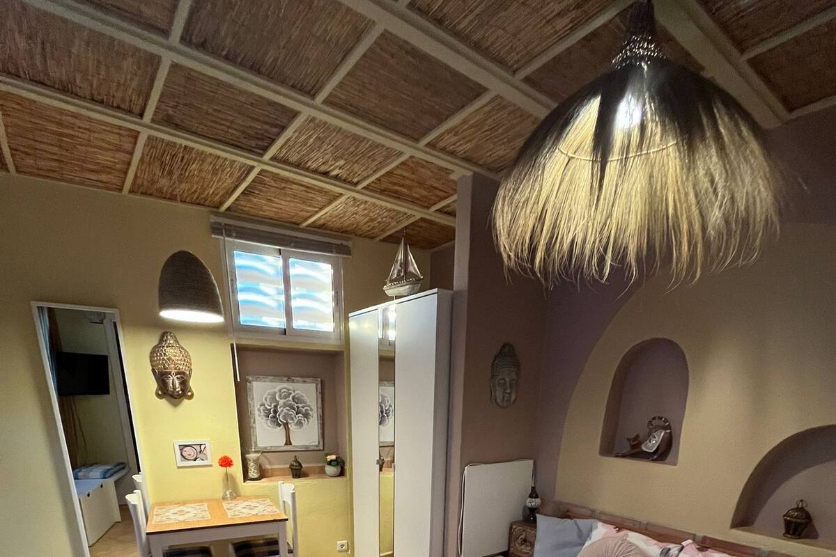 Un dormitorio con cama, escritorio y silla. Hay objetos decorativos en las paredes y un ventilador de techo.