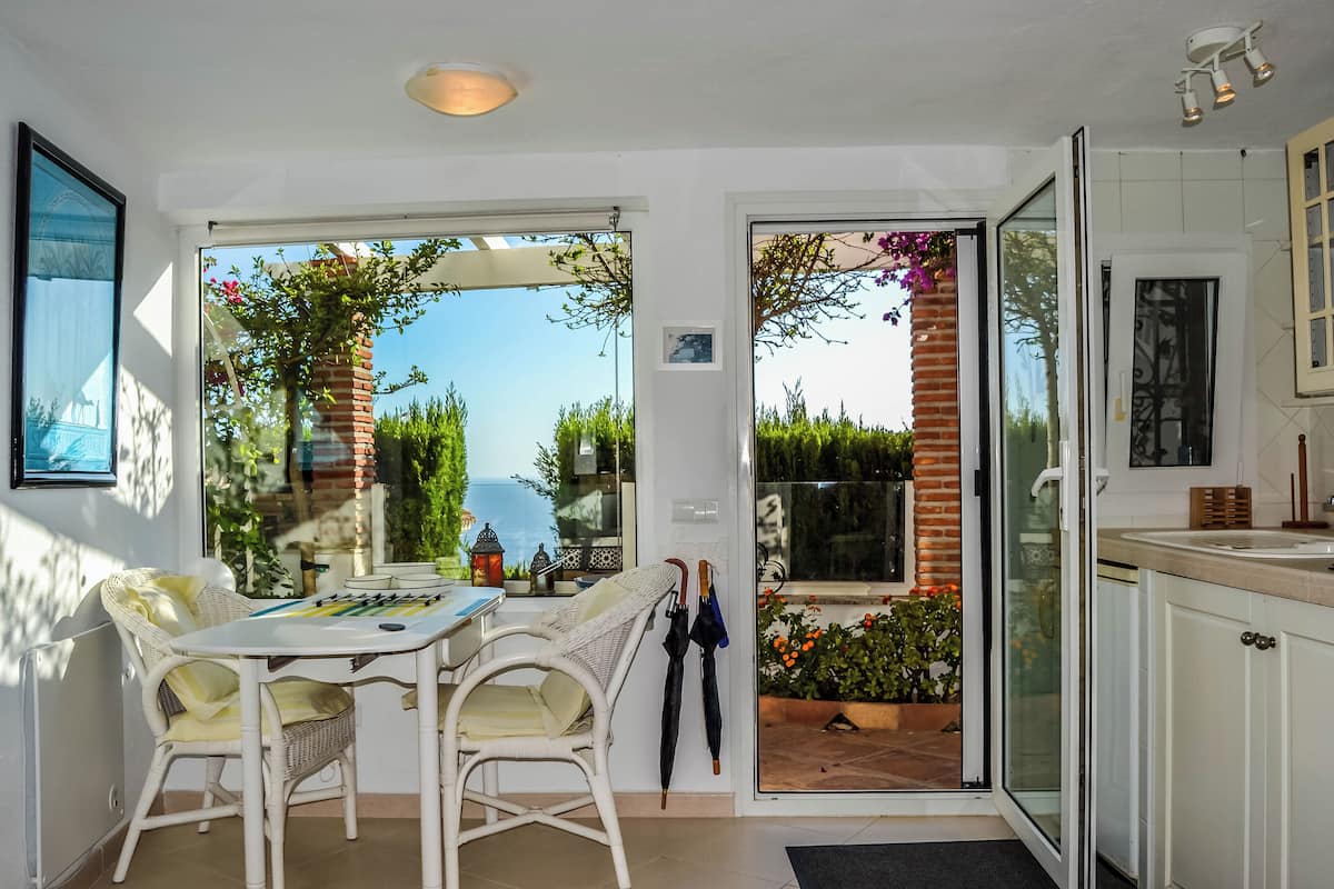Una cocina luminosa con comedor, ventanas amplias y vistas a zonas verdes.