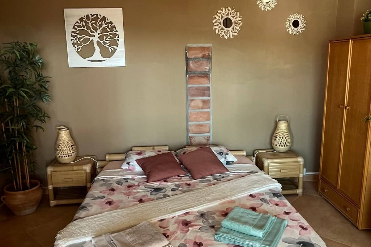 Un dormitorio con cama, lámpara colgante, adorno en la pared y planta en maceta.