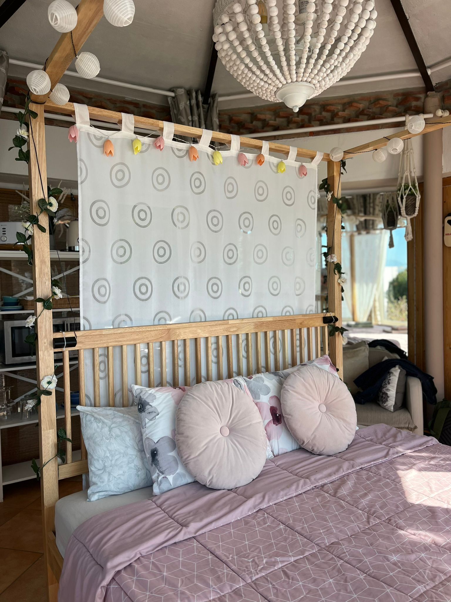 Un dormitorio con cama a dosel, una lámpara decorativa en el techo y vistas al exterior.