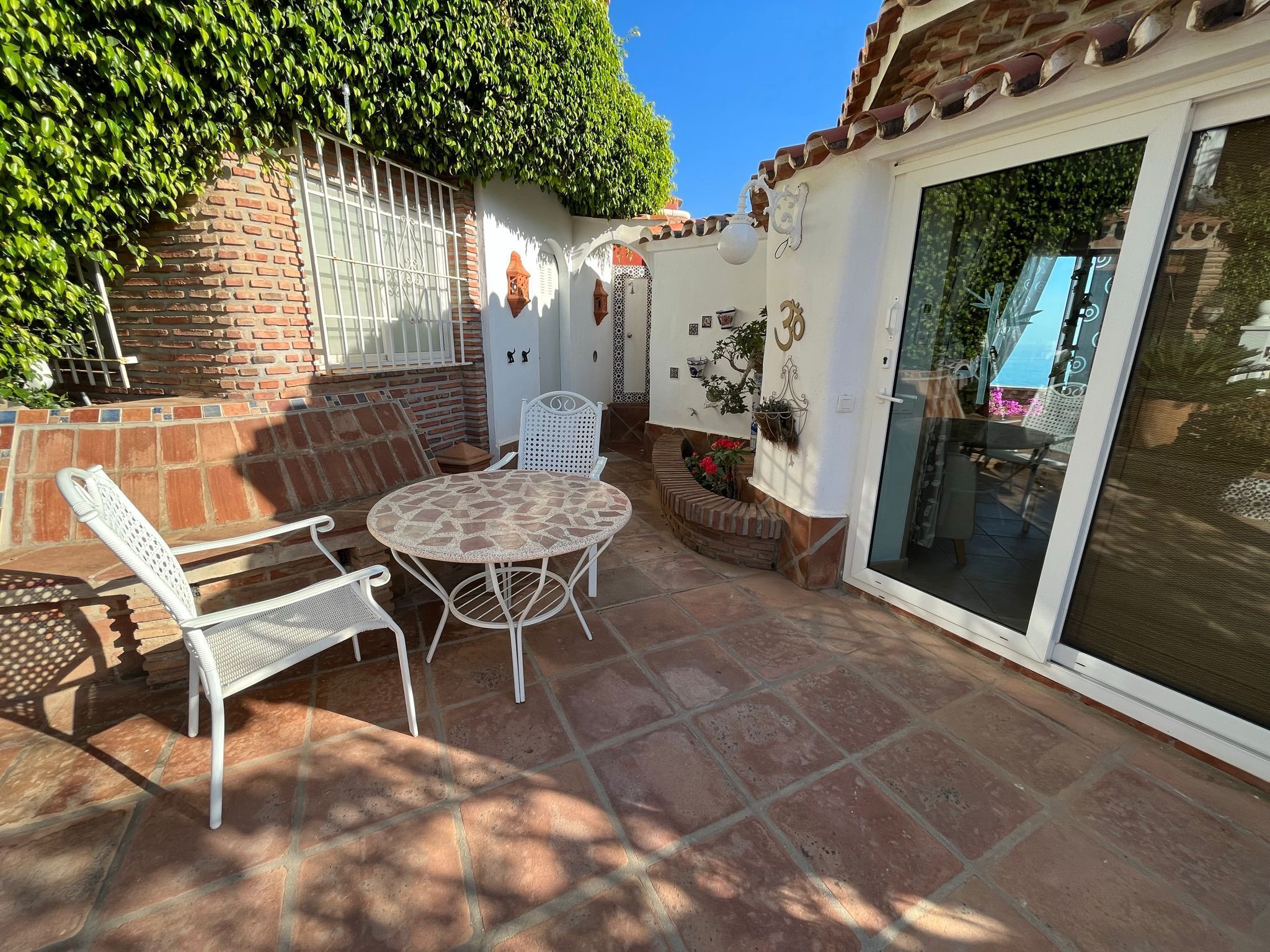Un patio con una mesa redonda y dos sillas, un muro de ladrillo y una puerta de cristal.