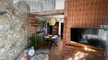 Un salon avec un téléviseur, un canapé et un coin repas.