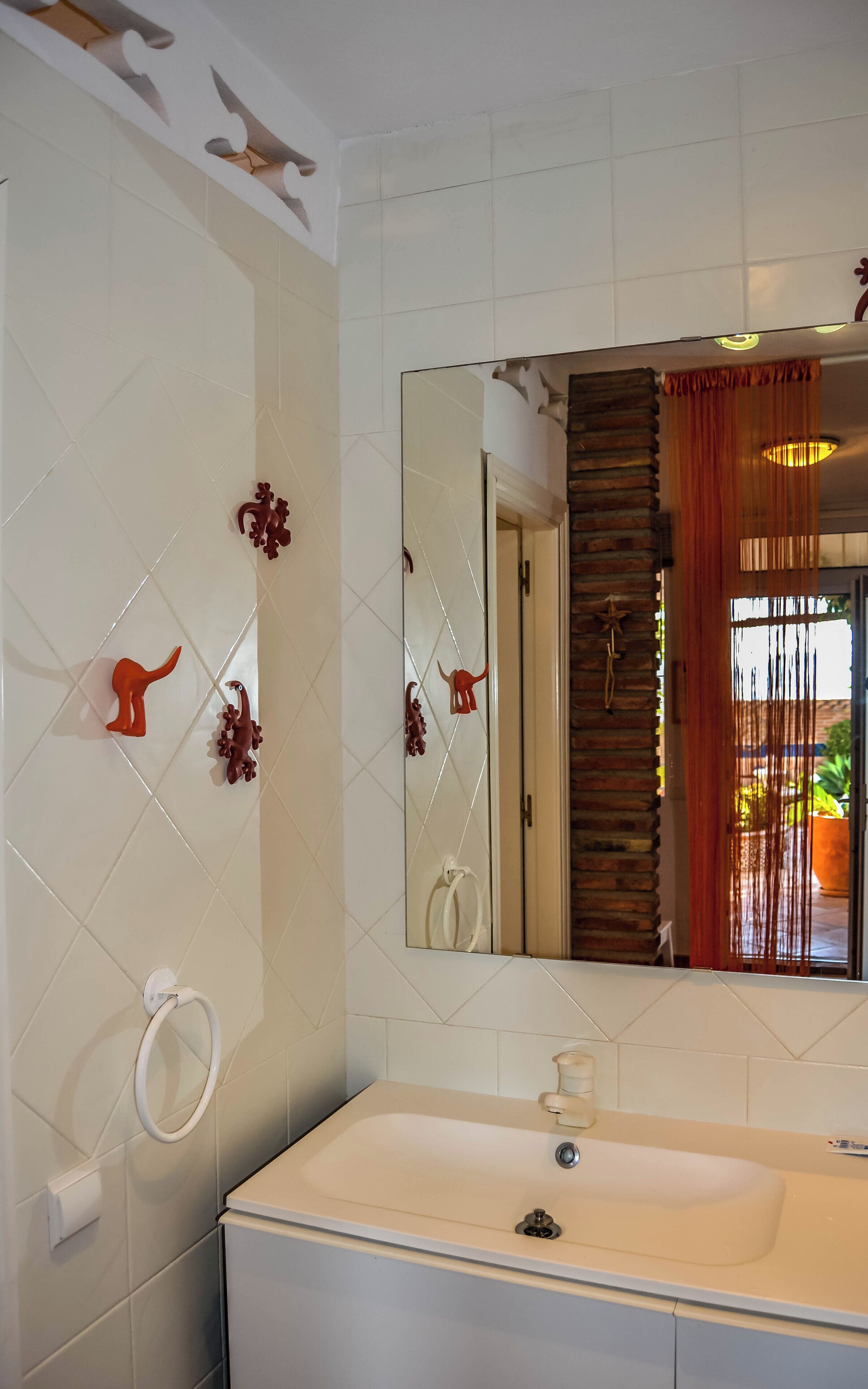 A bathroom with a white sink, a mirror, and decorative wall tiles.