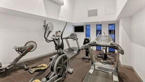 Une salle de sport moderne équipée de divers appareils de cardio, d’un tapis de course et d’un vélo d’appartement.