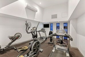 Un gimnasio moderno con máquinas de cardio, una bicicleta estática y una cinta de correr.