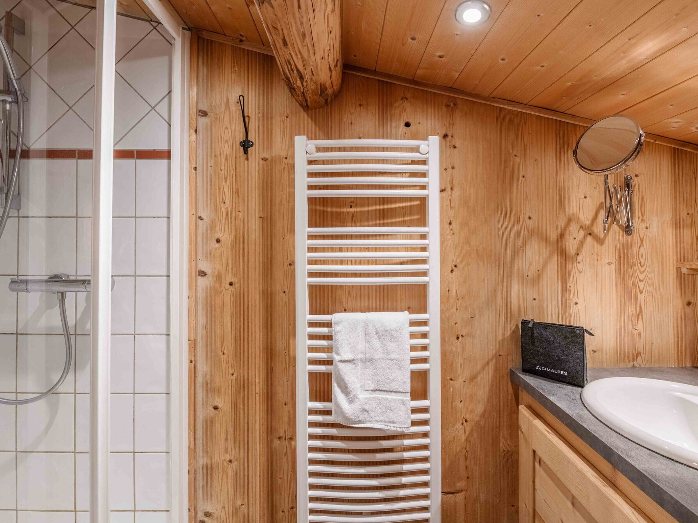 A wooden interior with a white towel rack, a sink, and a shower area.