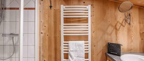 A wooden interior with a white towel rack, a sink, and a shower area.