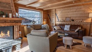 Interior acogedor de una cabaña de madera con chimenea, sofás de cuero y vistas a las montañas.