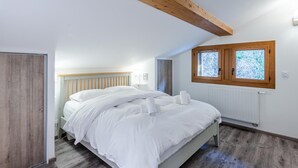 Un dormitorio con cama, vigas de madera en el techo, una ventana y un radiador.