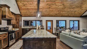 A spacious kitchen with a central island, wooden cabinets, and a stone countertop. - Sweet Magnolia~Sleeps 10~Game Area~2 Masters (Broken Bow)