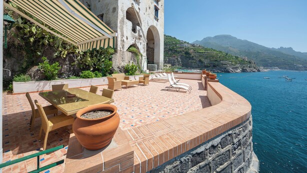 A terrace with outdoor furniture, a table, and a potted plant. - Villa Cavalluccio Marino (Campania)