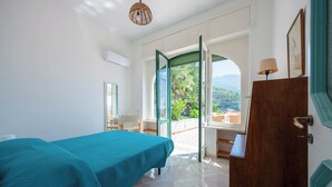 A bedroom with a bed, a desk, and a view of the outdoors. - Villa Cavalluccio Marino (Campania)