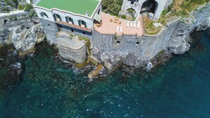 A coastal building with a green roof, stone walls, and a balcony overlooking the sea. - Villa Cavalluccio Marino (Campania)