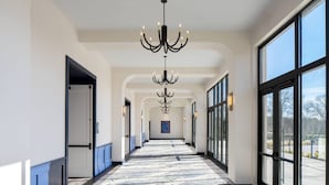 A hotel corridor with a patterned carpet, large windows, and a chandelier. - Trilith Guesthouse, Fayetteville, GA, A Tribute Portfolio (Fayetteville)