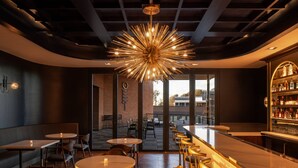 A modern bar area with a unique chandelier, seating arrangements, and a view through large windows. - Trilith Guesthouse, Fayetteville, GA, A Tribute Portfolio (Fayetteville)