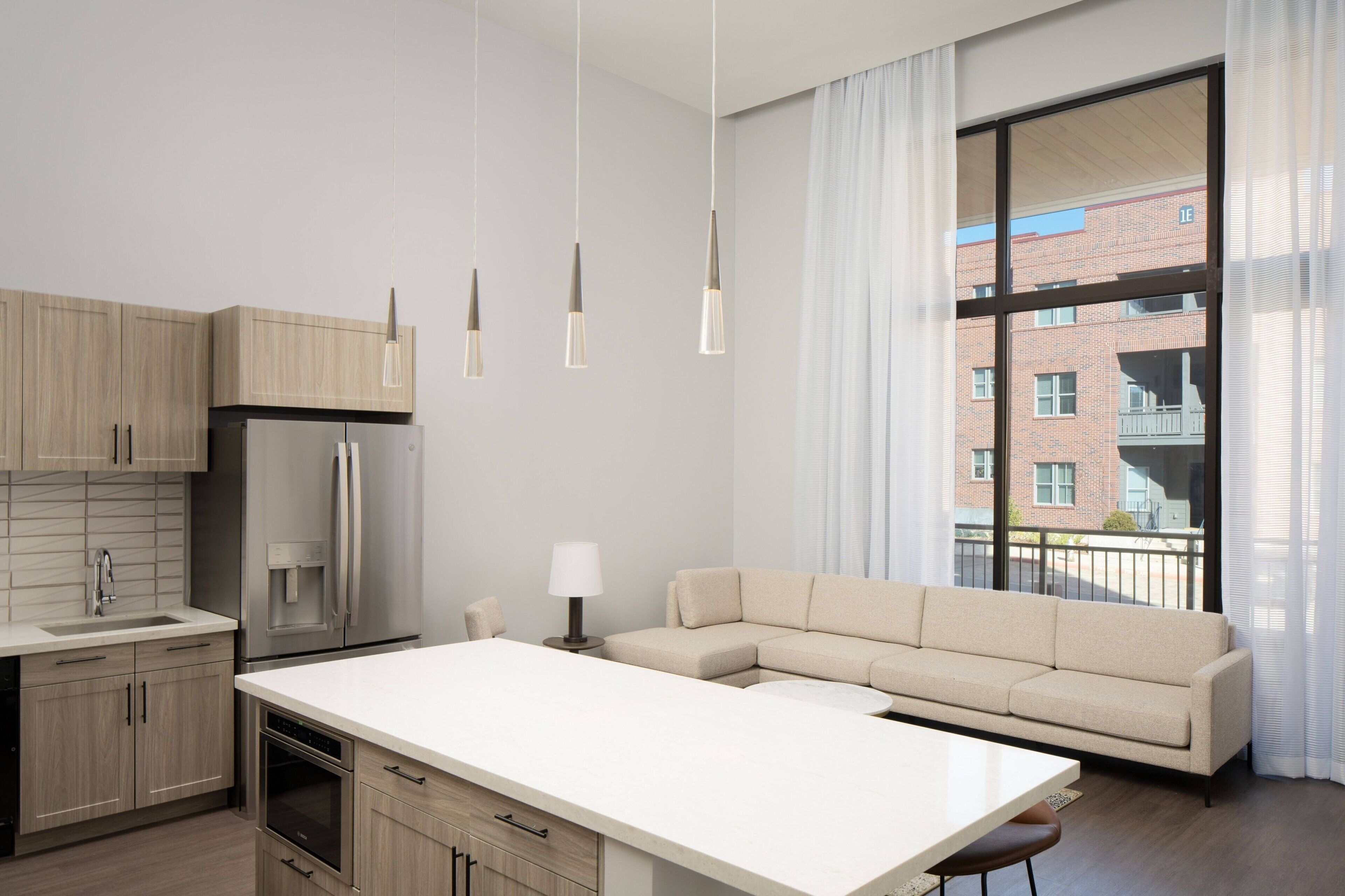 A modern kitchen with a large island, built-in appliances, and pendant lighting.