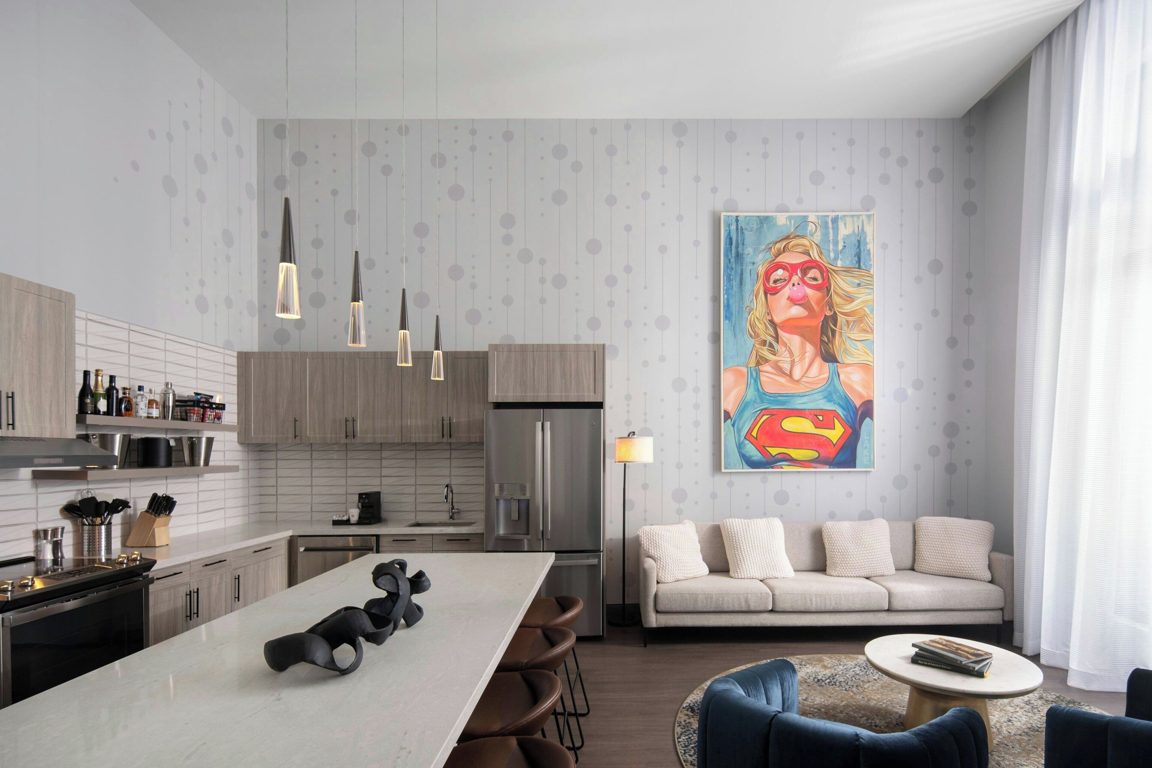 A modern kitchen with a central island, a dining area with a sofa and chairs, and a living room with a couch and a coffee table.