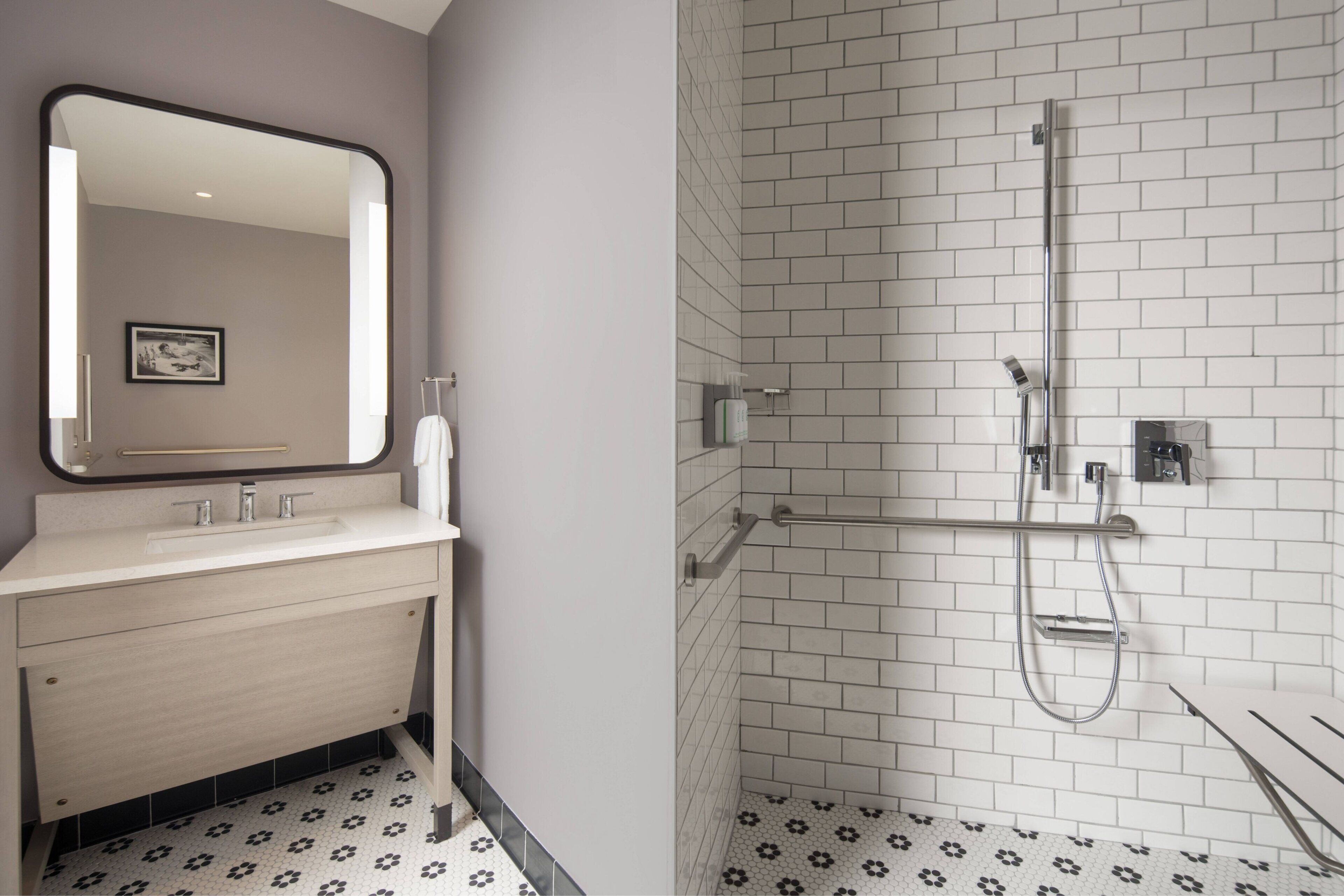 A modern bathroom with a white sink, mirror, and shower.