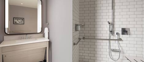 A modern bathroom with a white sink, mirror, and shower.
