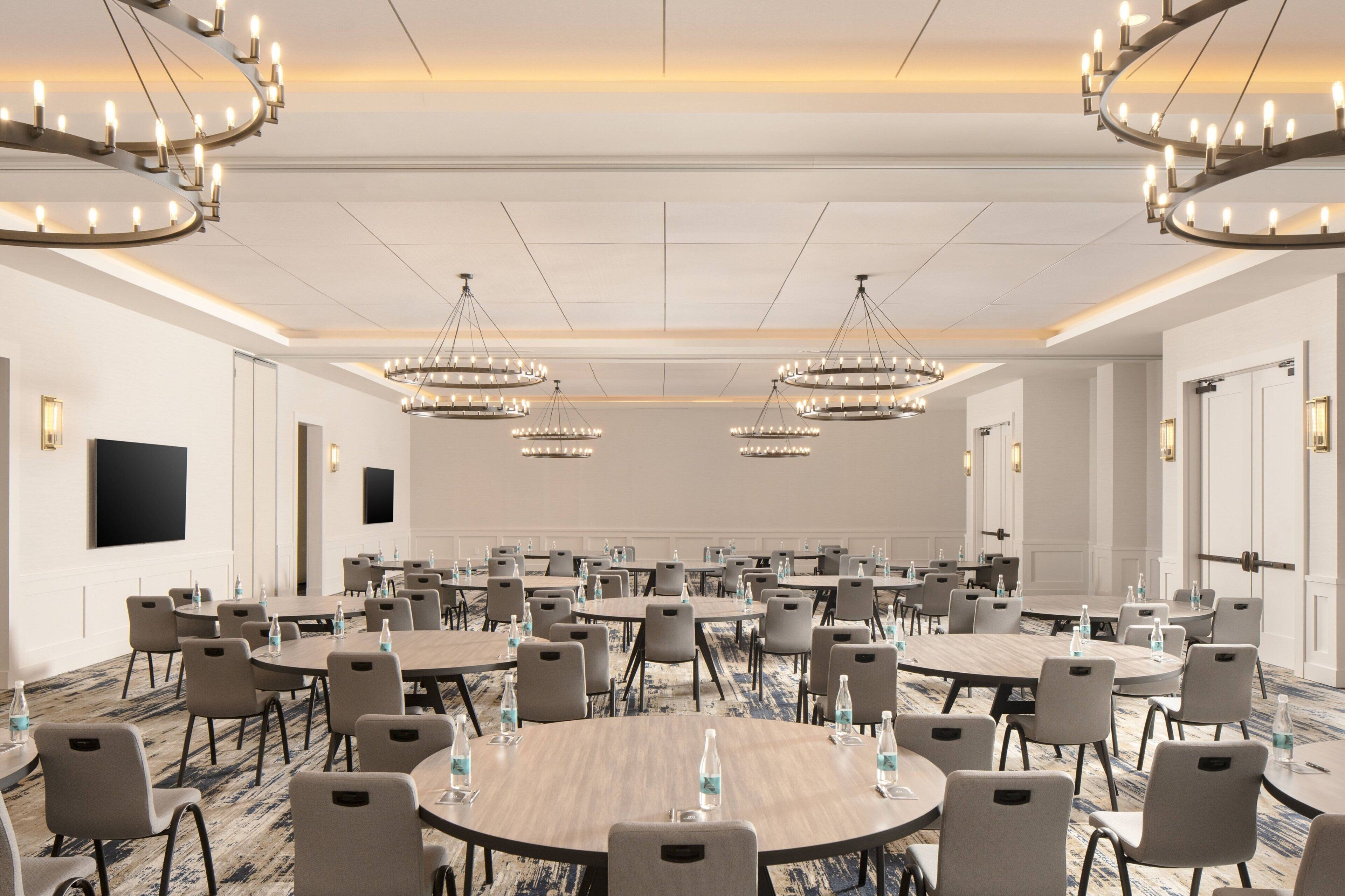 Un salón de conferencias con mesas redondas, sillas y candelabros.