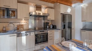 Una cocina moderna con electrodomésticos de acero inoxidable, armarios de madera y un comedor con manteles a rayas.