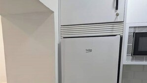 Una cocina con un refrigerador blanco, un microondas y una lavadora.