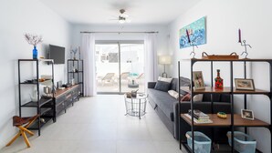 Un salon moderne avec un canapé, un téléviseur et des étagères remplies de divers objets.
