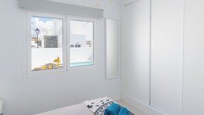 Une pièce dotée d’une grande fenêtre, d’un lit et d’un luminaire fixé au mur.